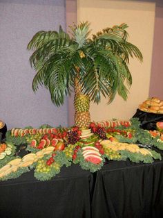 a palm tree sitting on top of a table covered in fruit