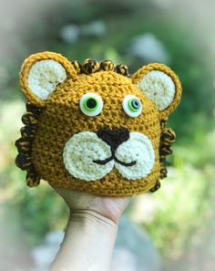 a hand holding up a crocheted animal hat with eyes on it's head