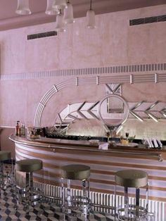 a bar with several stools in front of it and a mirror on the wall