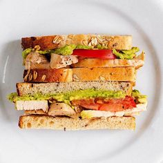 a white plate topped with two sandwiches covered in meat and veggie toppings