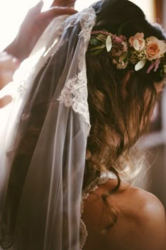 a woman wearing a veil and flowers in her hair is looking down at the ground