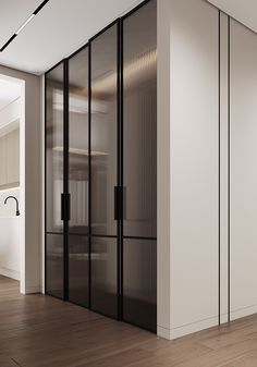 an empty room with glass partitions and wooden flooring on the side, in front of a white wall