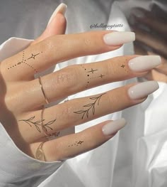 a woman's hand with four finger tattoos on her left thumb and two fingers in the middle