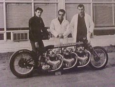 three men are standing next to a motorcycle