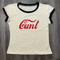 This 2000s Coca Cola Mall Goth Baby Tee Is Perfect For Anyone Who Loves The Y2k Aesthetic And Wants To Add A Touch Of Grunge To Their Wardrobe. The Graphic Print Features The Letter "L" And Is Designed To Look Like A Baby Girl. The Shirt Is Made Of A Blend Of Polyester And Cotton, Making It Comfortable And Machine Washable. It Has A Crew Neckline And Short Sleeves, Perfect For Casual Occasions In The Summer. The Shirt Is Available In Sizes S-Xl And Has A Regular Fit. The Beige Color And Vintage Graphic Tee Grunge, 2000s T Shirt Design, Iconic Graphic Tees, 90s Streetwear Women, 2000s Goth Aesthetic, Y2k Shirt Design, Downtown Clothes, 2000s T Shirt, Late 90s Fashion