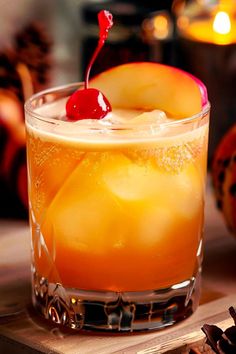 an apple cider cocktail is garnished with cherries