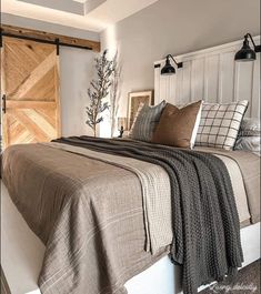 a bed with pillows and blankets on top of it next to a wooden headboard