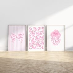 three pink and white wall art pieces on a wooden floor