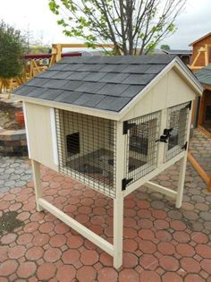 a small white house with a black roof and two large cages on the side of it