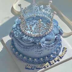 a blue and white cake with a tiara on top that says, first birthday