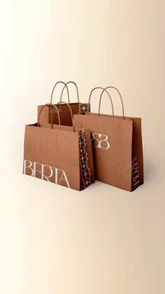 three brown paper bags with white letters and bows on the handles, sitting side by side