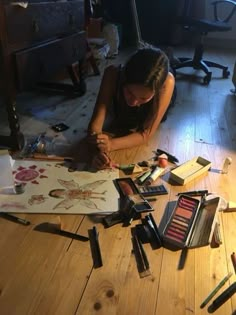 a woman is sitting on the floor working on some art work with crayons and pencils