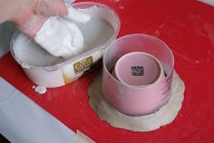 a person is using a cloth to wipe out some white paint on a red surface