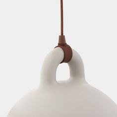 a white lamp with a brown cord hanging from it's end and the light is on