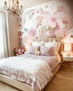 a bedroom with pink flowers on the wall and a chandelier hanging from the ceiling