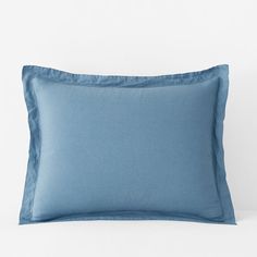 a blue pillow on a white bed