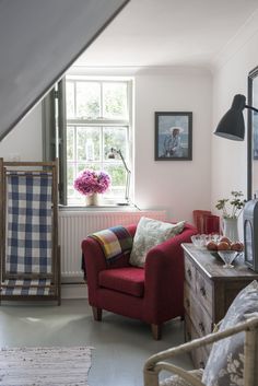 a red chair sitting next to a window in a living room