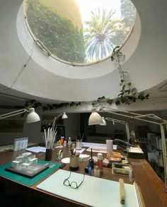 an office with plants growing on the ceiling and desk in front of it, under a circular skylight