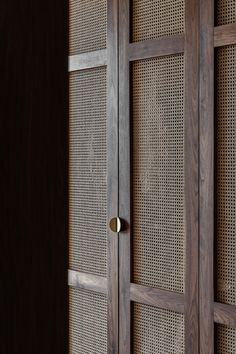 a wooden cabinet with metal handles and wicker panels on the front, in a dark room