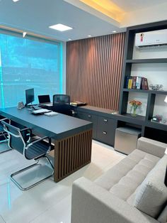 an office with two couches and a desk in front of a large glass window