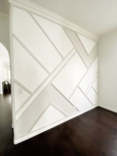 an empty room with wood floors and white walls in the corner is decorated with geometric paneling