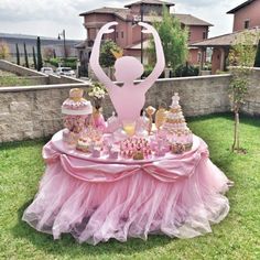 a table with cake and cupcakes on it in the middle of a yard