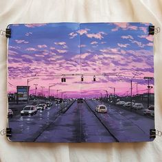 an open book with cars driving down the road at sunset or dawn, on top of a white sheet