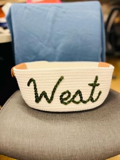 a white bowl with the word west written on it sitting on top of a chair