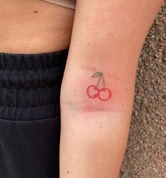 a small tattoo on the arm of a woman with two cherries painted on it