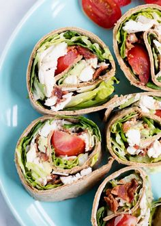 several wraps with meat, lettuce and tomatoes on a blue plate