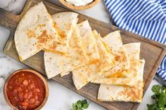 quesadillas on a cutting board with salsa and sour cream