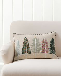 a white chair with a christmas tree pillow on it's back and two trees in the background