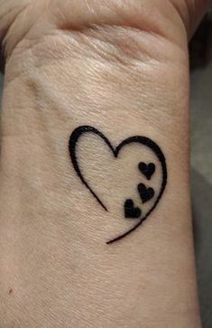 a small tattoo on the wrist of a person with a heart and three little hearts