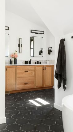 a bathroom with black and white tile flooring and wooden cabinetry on the wall