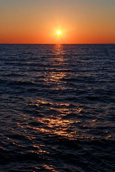 the sun is setting over the ocean as seen from a boat on the water's surface