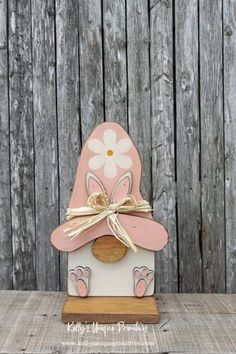 a pink and white birdhouse with a flower on it's top sitting on a wooden