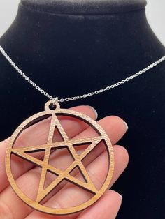 a hand holding a pentagram pendant on a chain