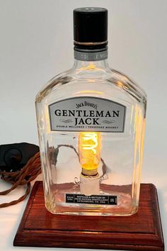 a bottle of gentleman jack sitting on top of a wooden stand next to a cord