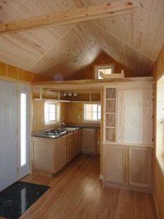 an empty kitchen and living room in a small cabin with wood paneling on the walls