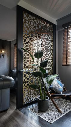 a living room with a plant in the corner and a decorative screen on the wall