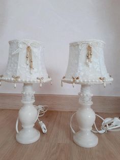 two white lamps sitting on top of a wooden floor next to each other, one has a cord attached to it and the other is plugged in