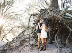 a man and woman standing next to each other in front of a tree trunk structure