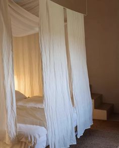 a bed with white drapes hanging from it's sides