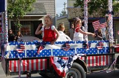 some people are riding in the back of a truck decorated with american flags and stars