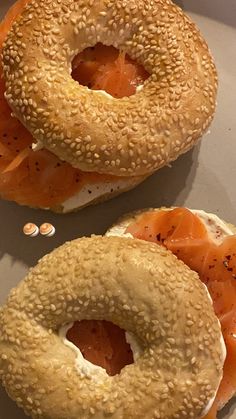 two bagels with salmon and cream cheese on them sitting on a white plate next to each other