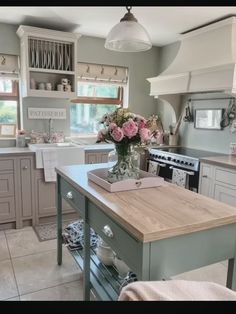 a kitchen filled with lots of counter space and flowers in a vase on the island