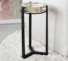 a glass and metal side table on a white rug