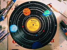 a record with planets on it surrounded by crayons and markers