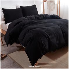 a black comforter with pom - poms on the edges and two pillows