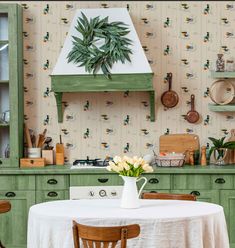 a kitchen with green cabinets and wallpaper has a potted plant on the stove